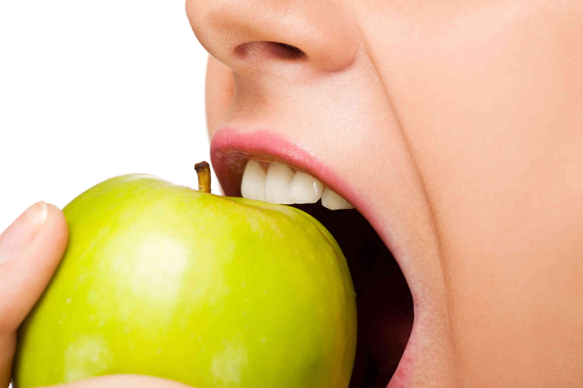 Frau beißt in einen grünen Apfel mit gesunden Zähnen