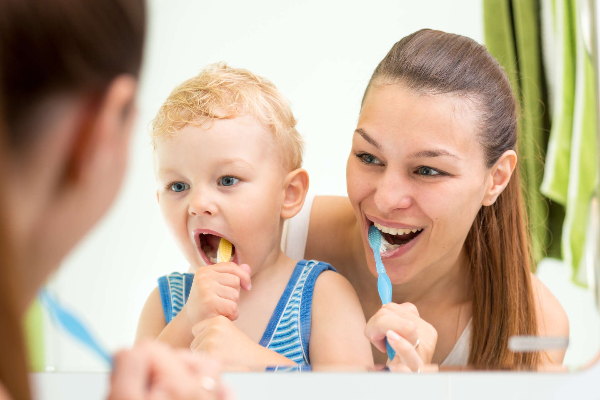 Mutter putzt sich mit ihrem Kind die Zähne